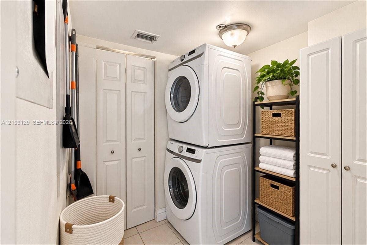 1627 Brickell Avenue, #2005, Miami, FL 33129 Laundry area featuring floor-to-ceiling white paneled storage cabinetry, tile flooring, and a flush-mount dome light fixture