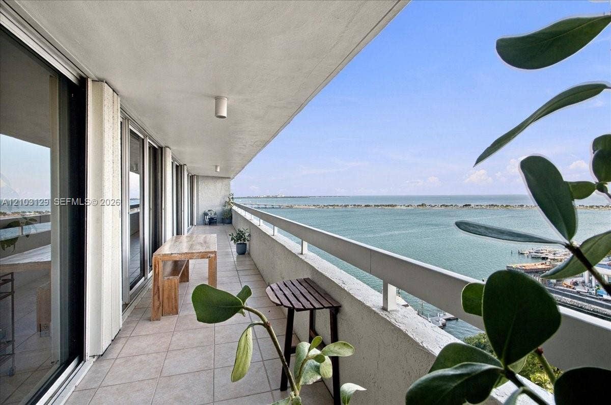 1627 Brickell Avenue, #2005, Miami, FL 33129 Expansive covered balcony featuring tile flooring, a concrete ceiling with integrated lighting, and a metal railing overlooking the water