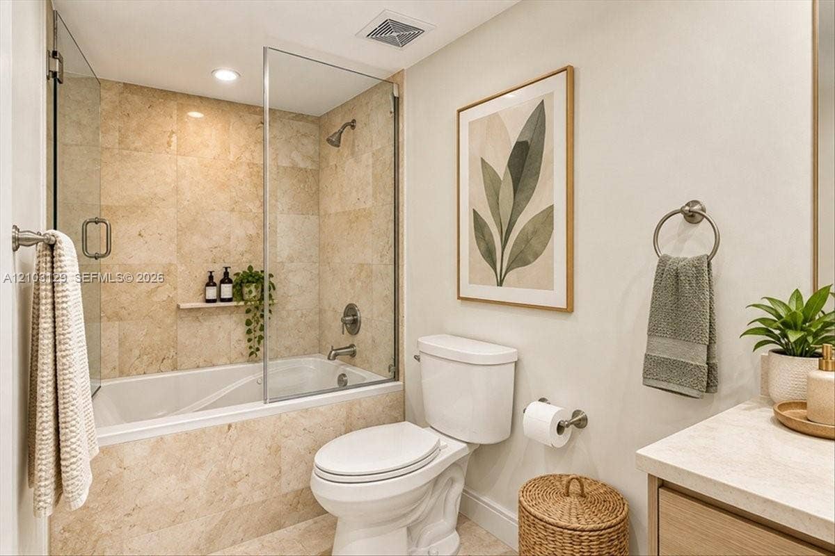 1627 Brickell Avenue, #2005, Miami, FL 33129 Full-height natural stone tile shower surround, frameless glass door, built-in stone recessed shelving, and a stone-topped vanity