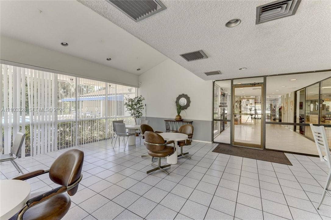 Large-format tile flooring, expansive floor-to-ceiling windows, vaulted ceilings, and glass-paneled entry doors