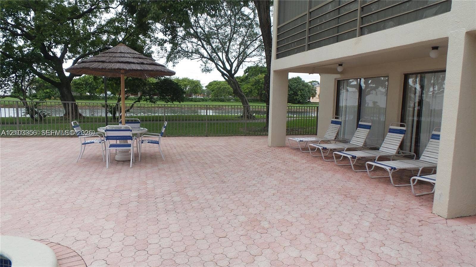 Spacious paved patio featuring integrated hardscaping, metal perimeter fencing, and a partially covered exterior area