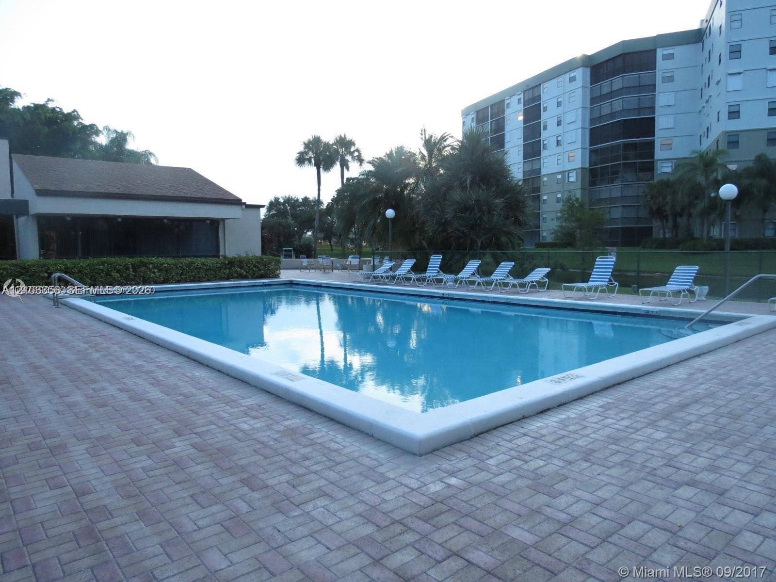 Rectangular swimming pool featuring a brick-paver deck and perimeter fencing