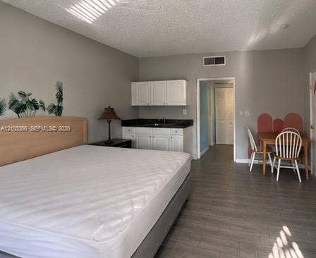 26 Diplomat Parkway, #2342, Hallandale Beach, FL 33009 Interior space featuring wood-finish flooring, white cabinetry with dark countertops, and a built-in sink