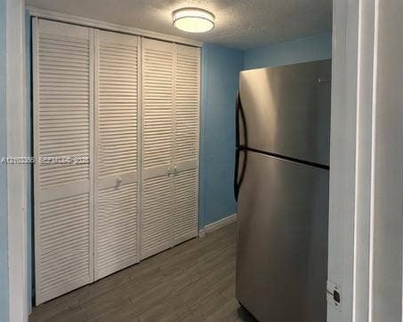 26 Diplomat Parkway, #2342, Hallandale Beach, FL 33009 Triple-panel white louvered closet doors, stainless steel refrigerator, and wood-finish flooring illuminated by a flush-mount ceiling fixture