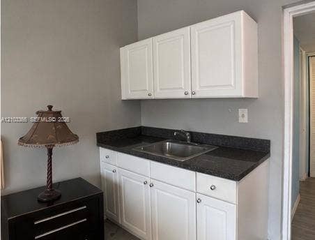 26 Diplomat Parkway, #2342, Hallandale Beach, FL 33009 White cabinetry featuring shaker-style doors, dark stone-finish countertop, and stainless steel undermount sink