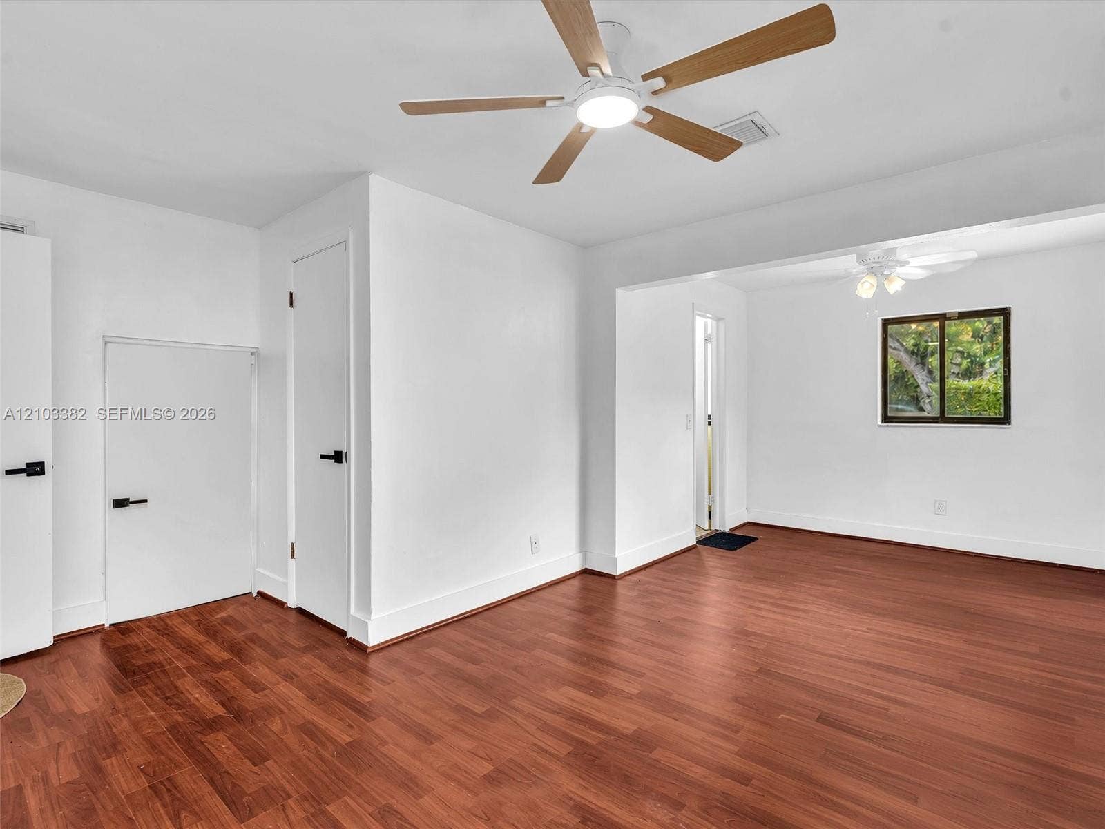 1545 Mantua Avenue, Coral Gables, Coral Gables, FL 33146 Primary bedroom featuring wood-finish flooring, two ceiling fans with integrated lighting, and doors accented with matte black hardware. House for rent in Coral Gables. House for rent listed by Realtor.