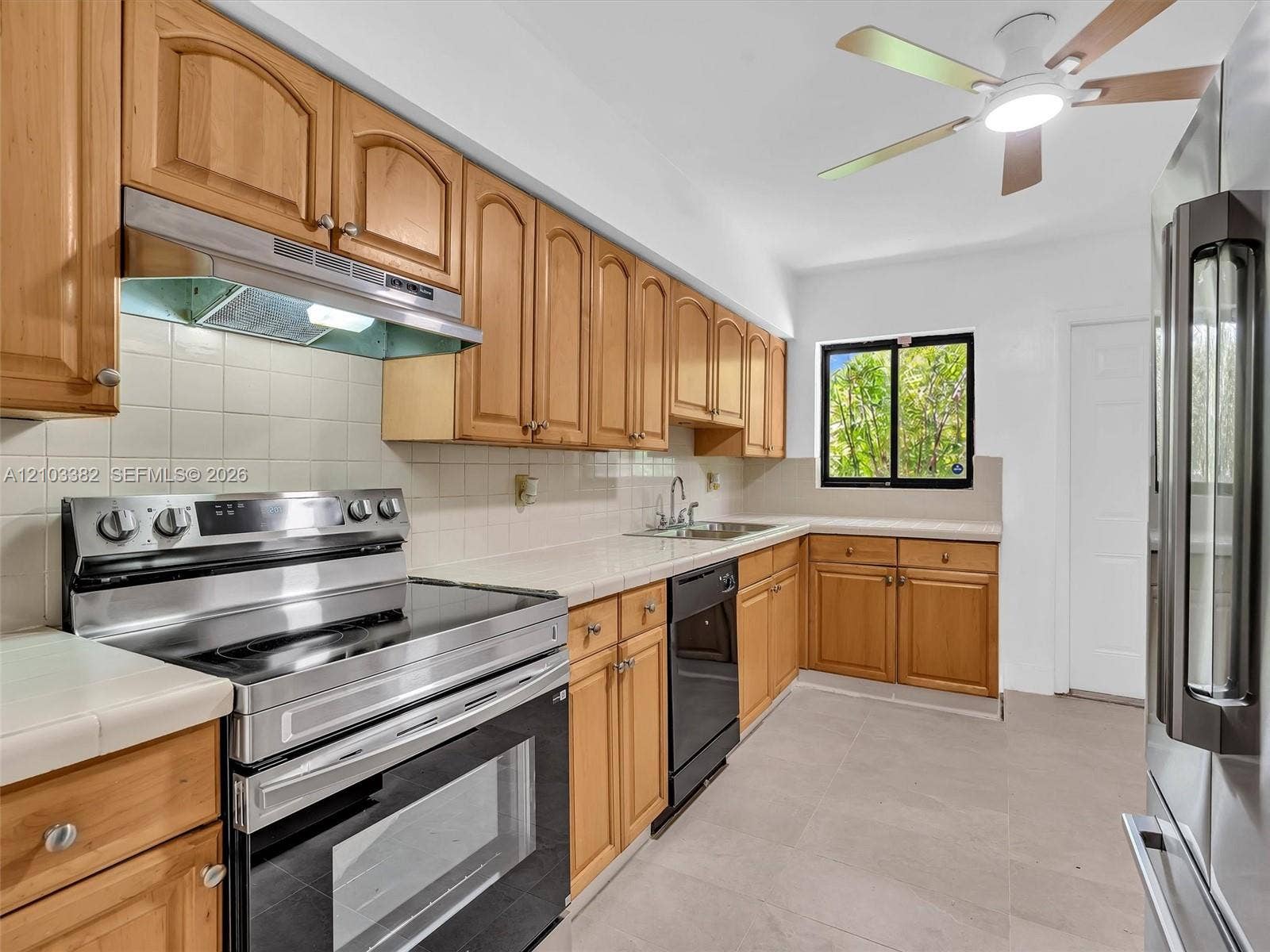 1545 Mantua Avenue, Coral Gables, Coral Gables, FL 33146 Spaceous kitchen featuring tile countertops, stainless steel appliances, a ceiling fan with integrated lighting, and tile flooring. House for rent in Coral Gables. House for rent listed by Realtor.