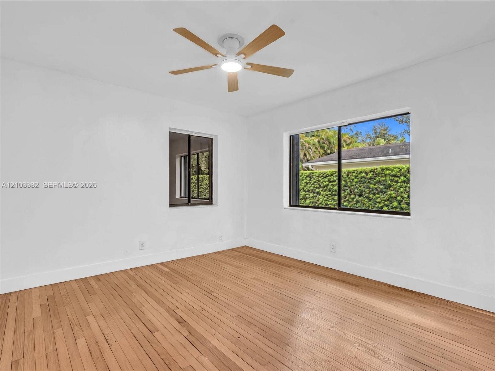 1545 Mantua Avenue, Coral Gables, Coral Gables, FL 33146 East rear bedroom. Wood-finish flooring, white walls, dual windows with black frames, and a ceiling-mounted fan with integrated lighting. House for rent in Coral Gables. House for rent listed by Realtor