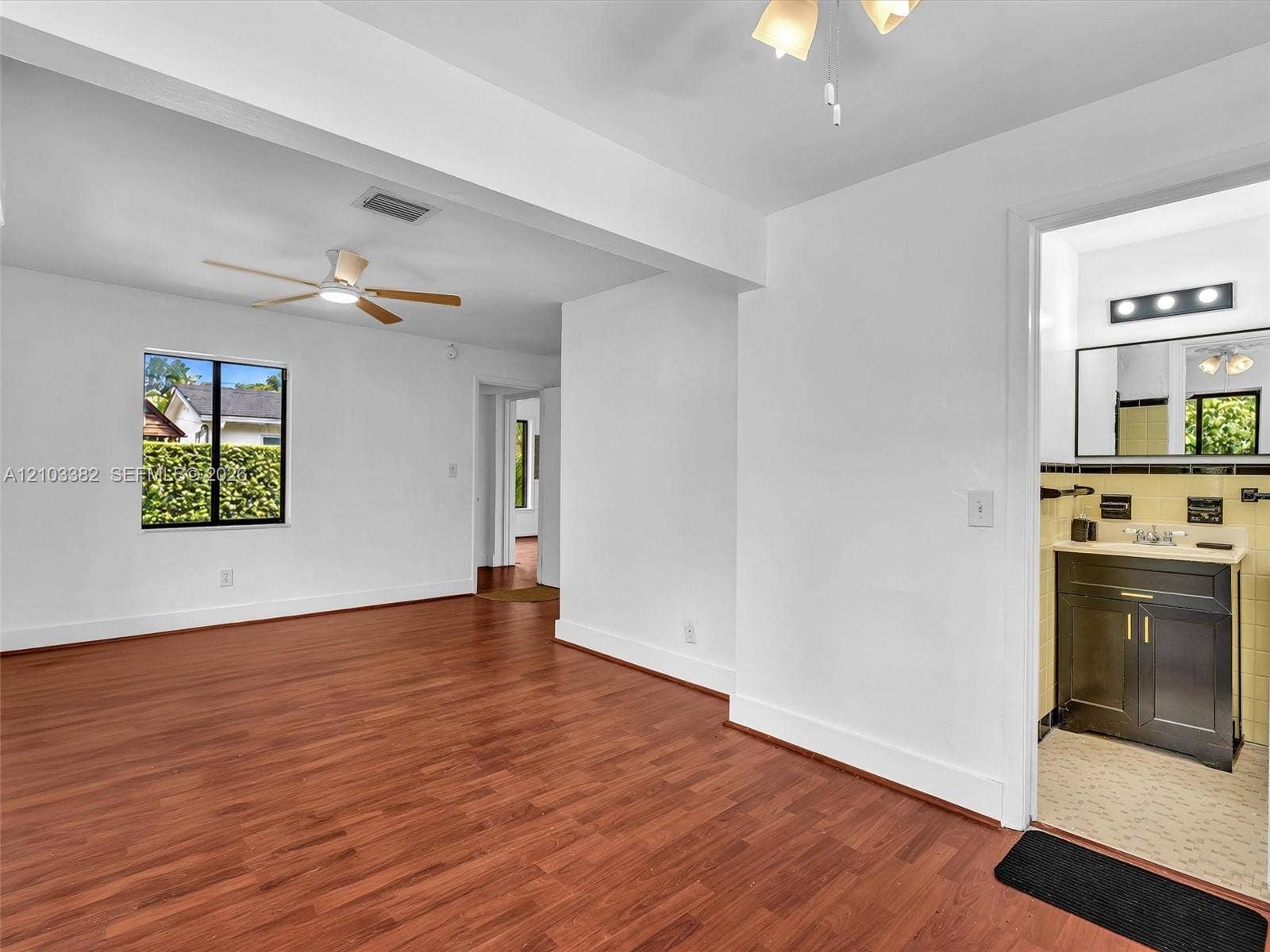 1545 Mantua Avenue, Coral Gables, Coral Gables, FL 33146 Showing seating area in primary bedroom with en suite bath, and walk-in closet. Wood-finish flooring, ceiling fan with integrated lighting, and neutral wall tones