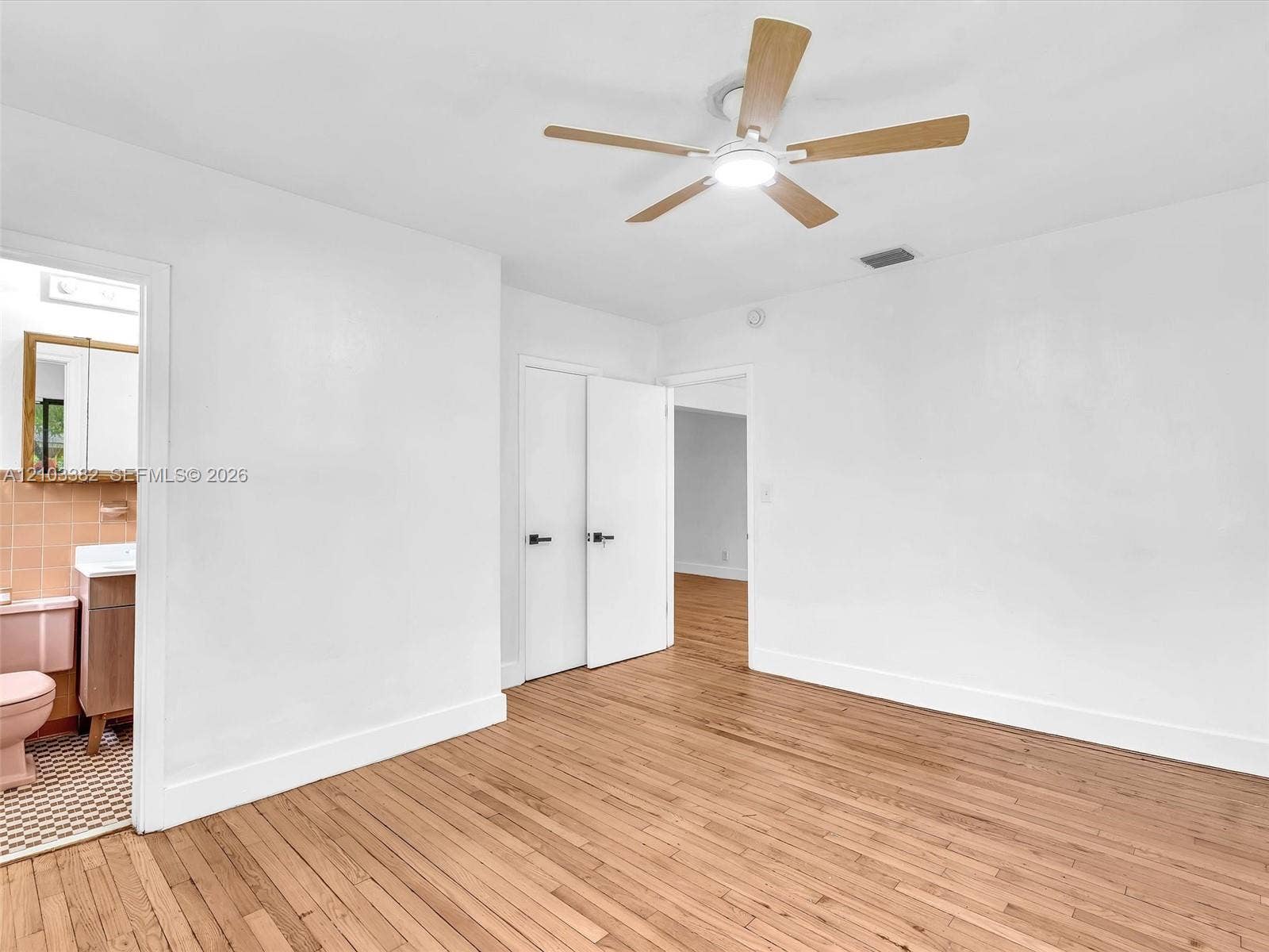 1545 Mantua Avenue, Coral Gables, Coral Gables, FL 33146 West front bedroom with en-suite bath and closet. Wood-finish flooring throughout, ceiling fan with integrated lighting, and white interior doors with matte black hardware. House for rent in Coral Gables. House for rent listed by Realtor.