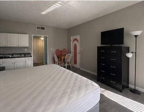Built-in kitchenette featuring white cabinetry, dark stone-finish countertops, and an integrated sink, complemented by wood-finish flooring