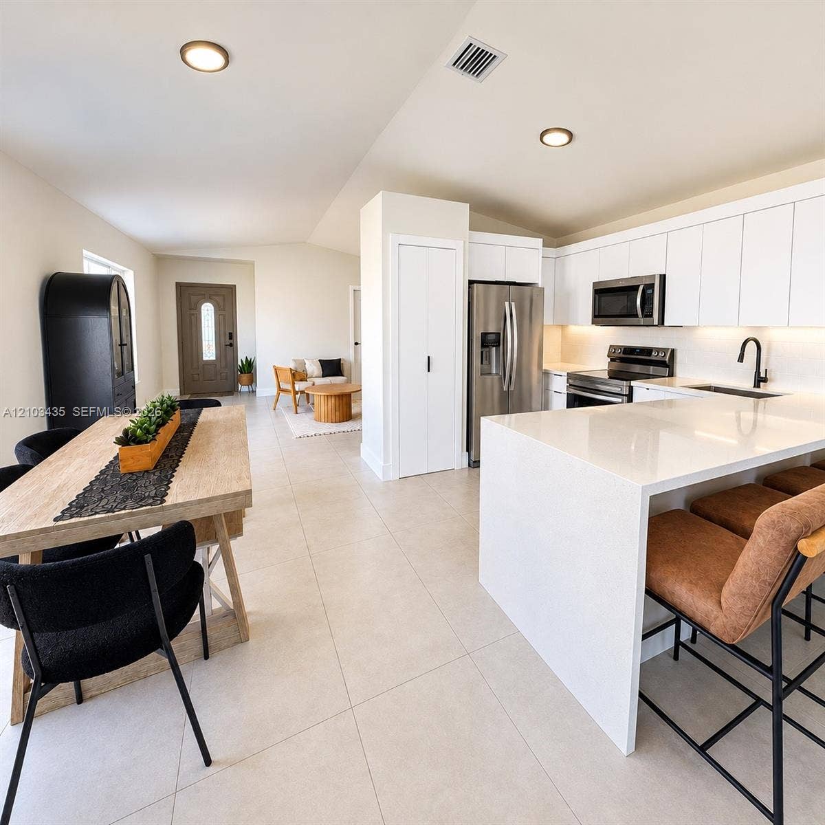 Miami, FL 33177 Modern kitchen featuring a waterfall-edge stone island, white flat-panel cabinetry, stainless steel appliances, and large-format tile flooring