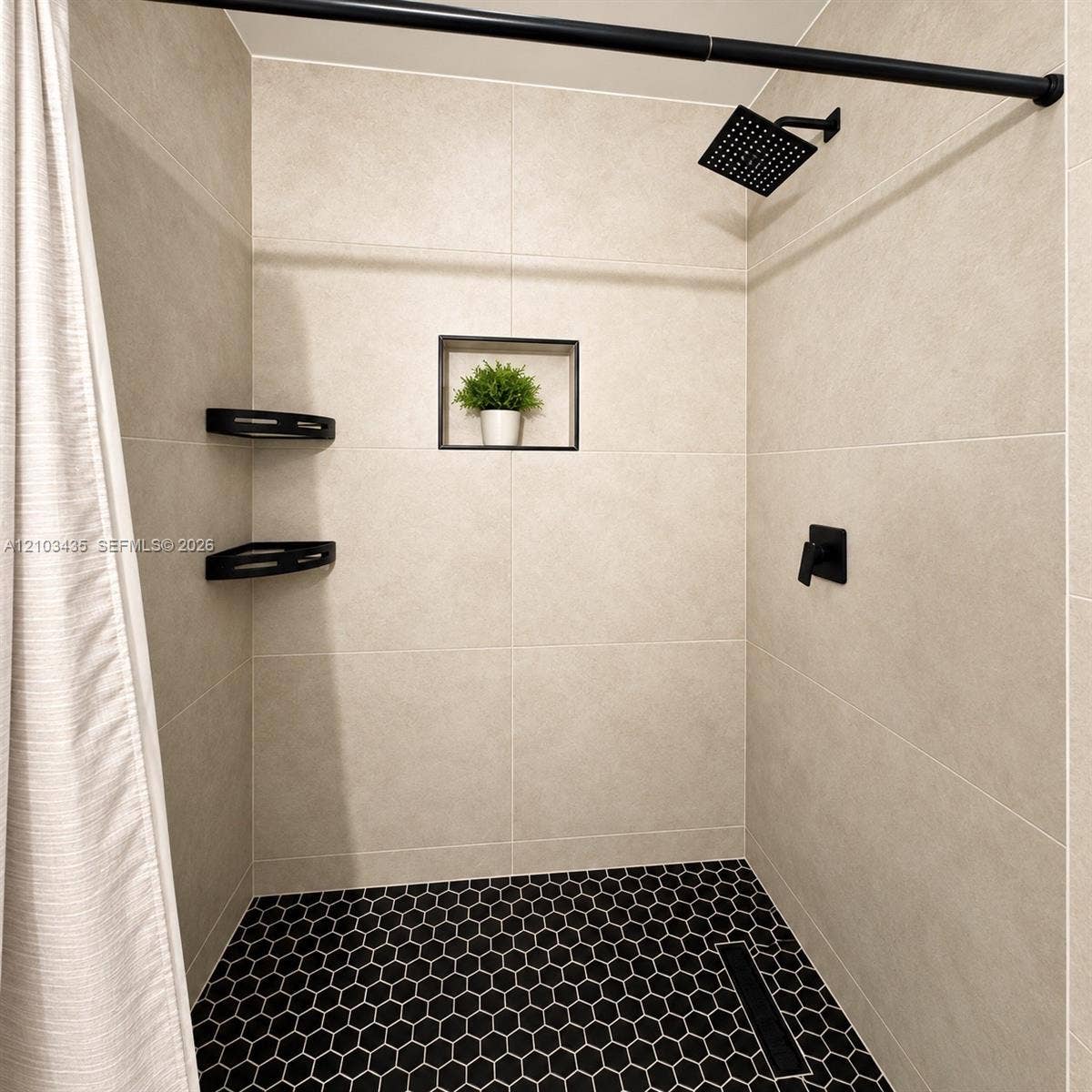 Miami, FL 33177 Shower stall featuring large-format beige wall tile, hexagonal black floor tile, matte black rainfall shower head, integrated wall niche, and corner shelving