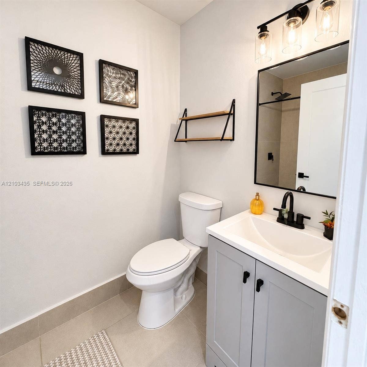 Miami, FL 33177 Grey vanity featuring a white basin, matte black faucet, rectangular mirror with a black frame, and glass-shade light fixture