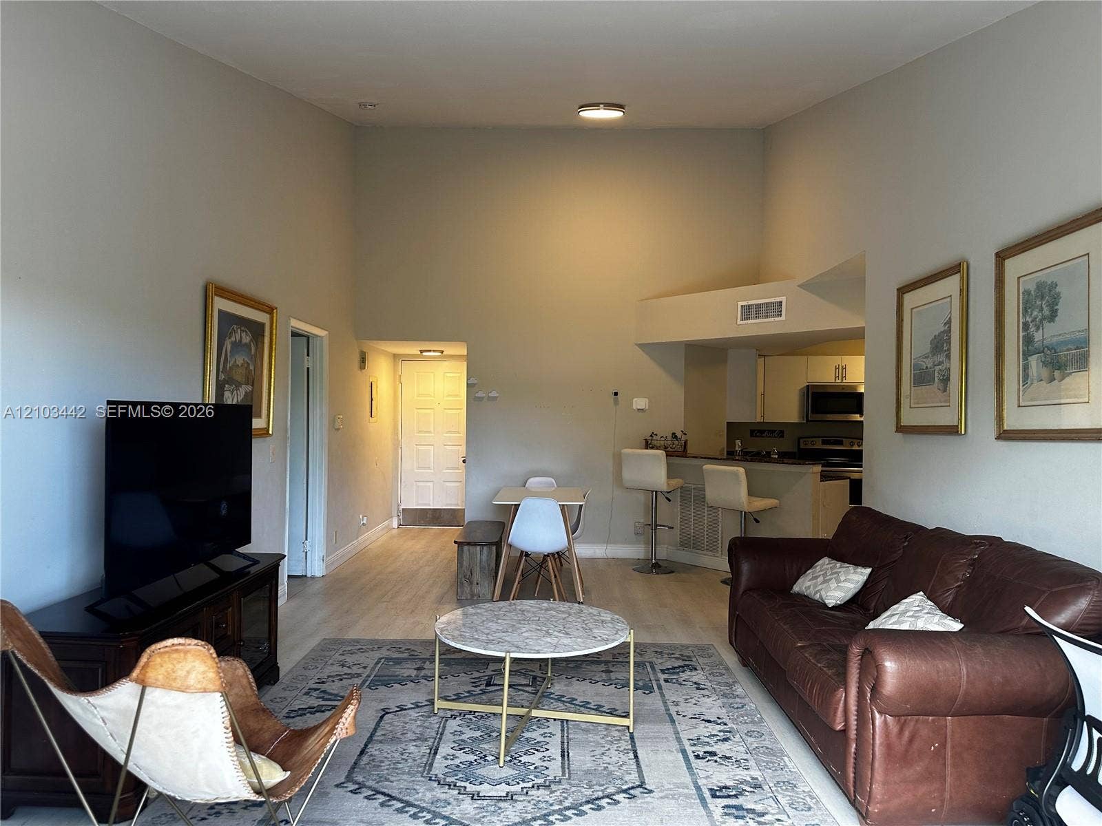 8721 Wiles Road, #303, Coral Springs, FL 33067 High vaulted ceilings, wood-finish flooring, and open-concept layout featuring a kitchen breakfast bar