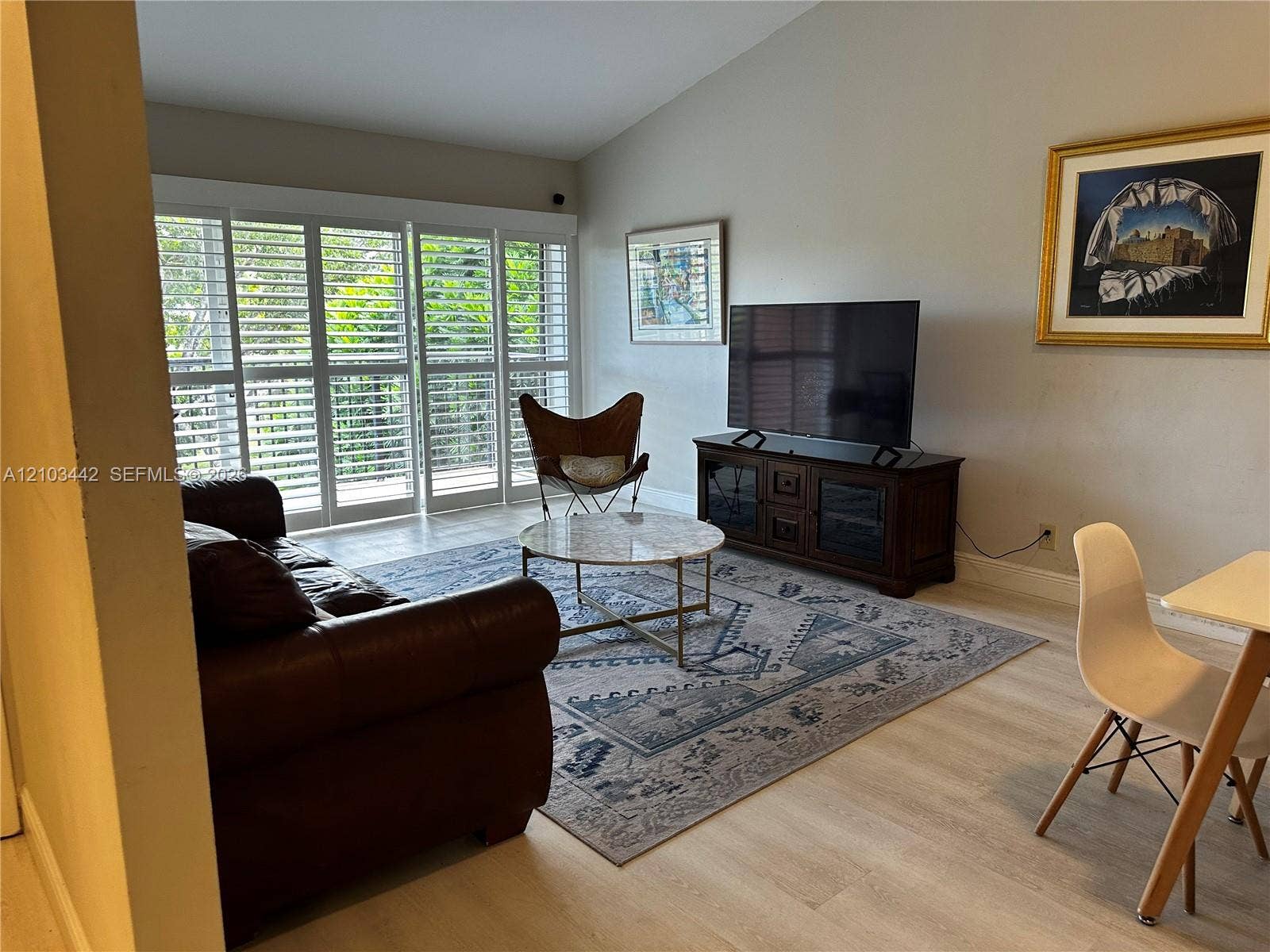 8721 Wiles Road, #303, Coral Springs, FL 33067 Vaulted ceilings, wood-finish flooring, and floor-to-ceiling sliding glass doors featuring custom plantation shutters