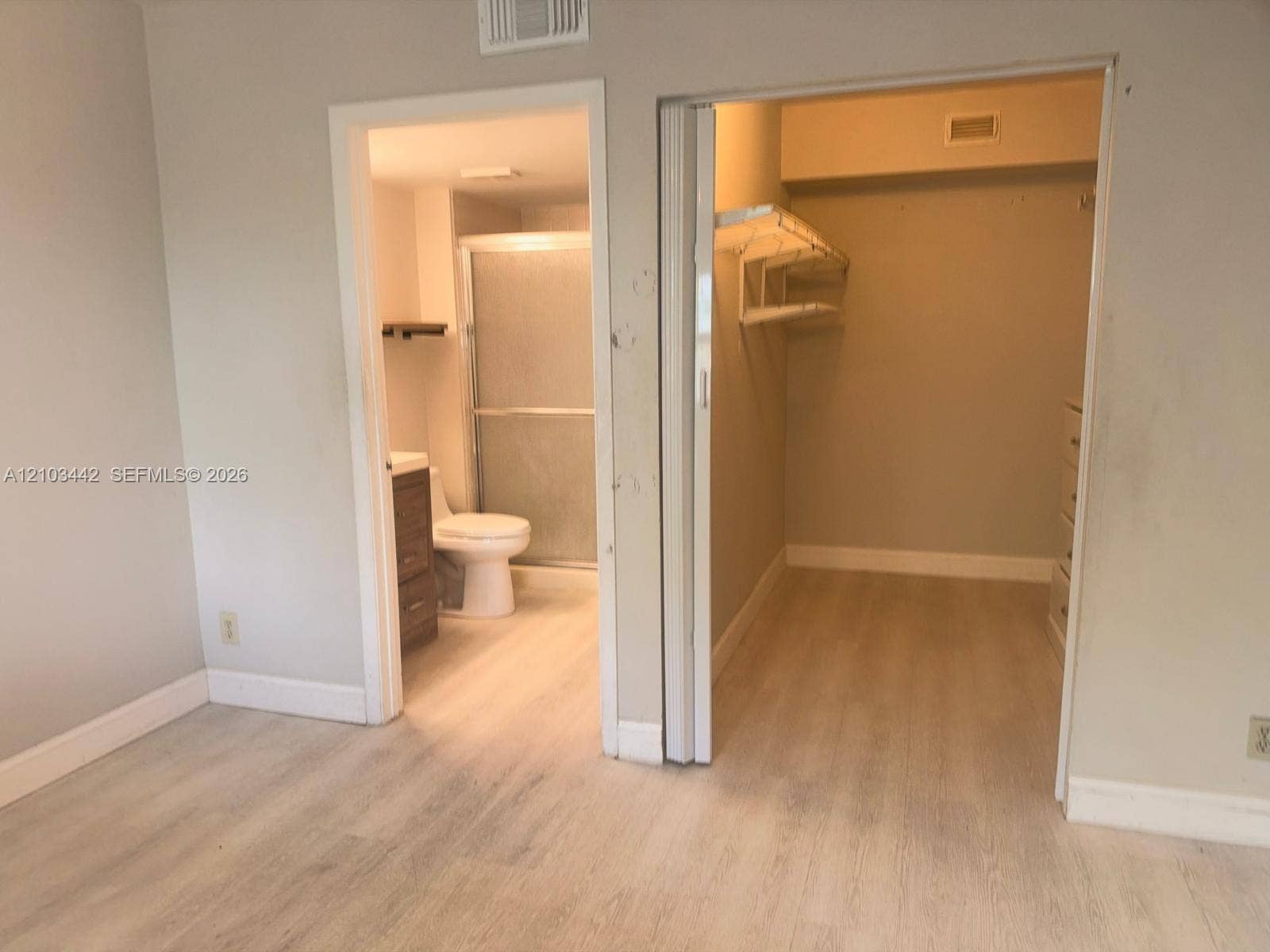 8721 Wiles Road, #303, Coral Springs, FL 33067 Interior space featuring wood-finish flooring, a bathroom with a glass-enclosed shower, and a walk-in closet with built-in shelving