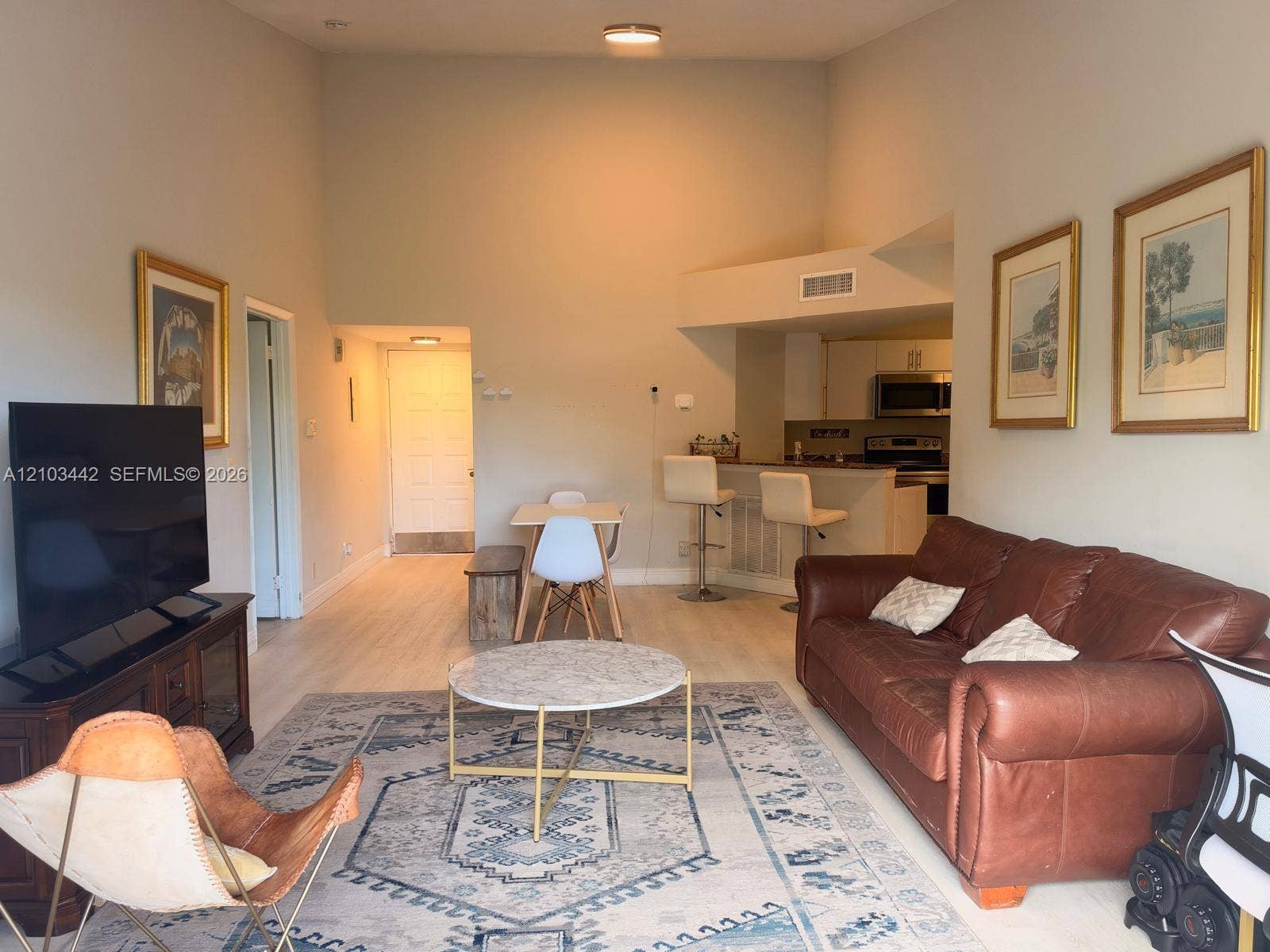 8721 Wiles Road, #303, Coral Springs, FL 33067 Vaulted ceilings featuring a neutral paint palette, wood-finish flooring, and a breakfast bar with stone-surface countertop