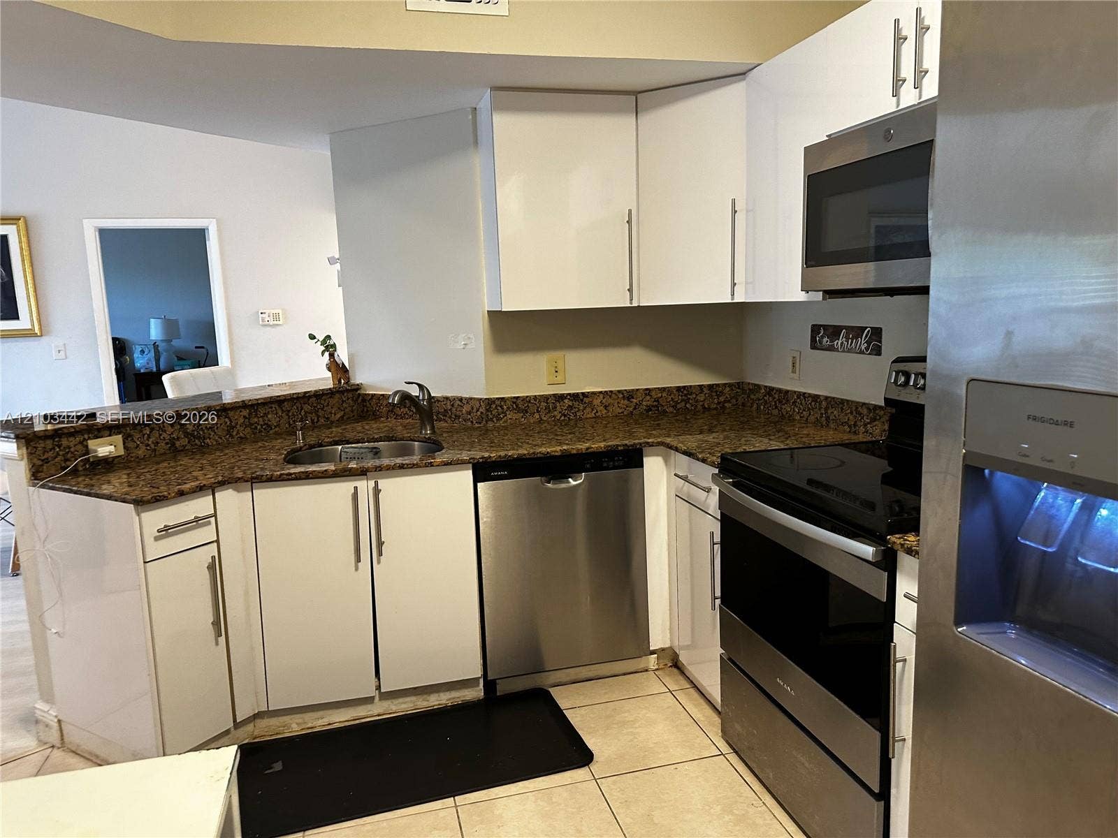 8721 Wiles Road, #303, Coral Springs, FL 33067 Kitchen featuring white flat-panel cabinetry, stone countertops, stainless steel appliances, a stainless steel undermount sink with a pull-down faucet, and tile flooring