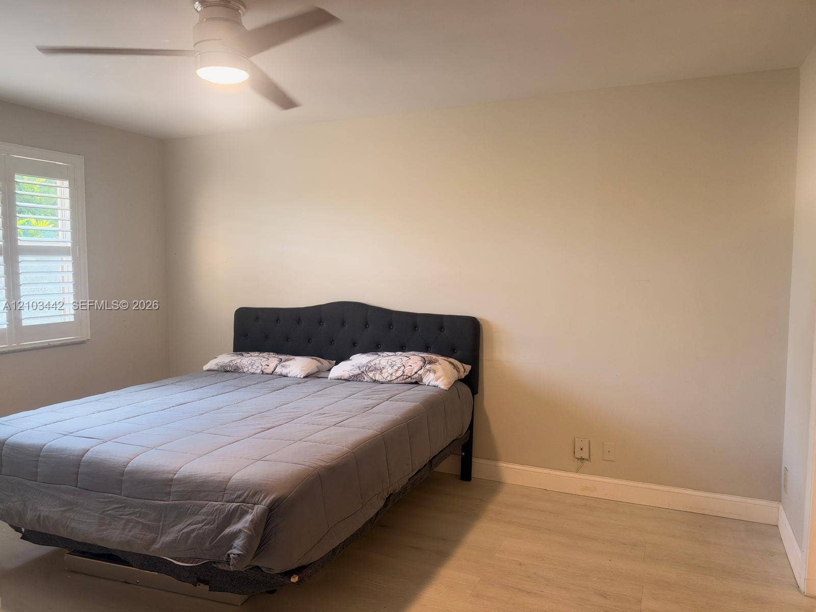8721 Wiles Road, #303, Coral Springs, FL 33067 Neutral wall palette featuring wood-finish flooring, plantation shutters, and a central ceiling fan with an integrated light fixture