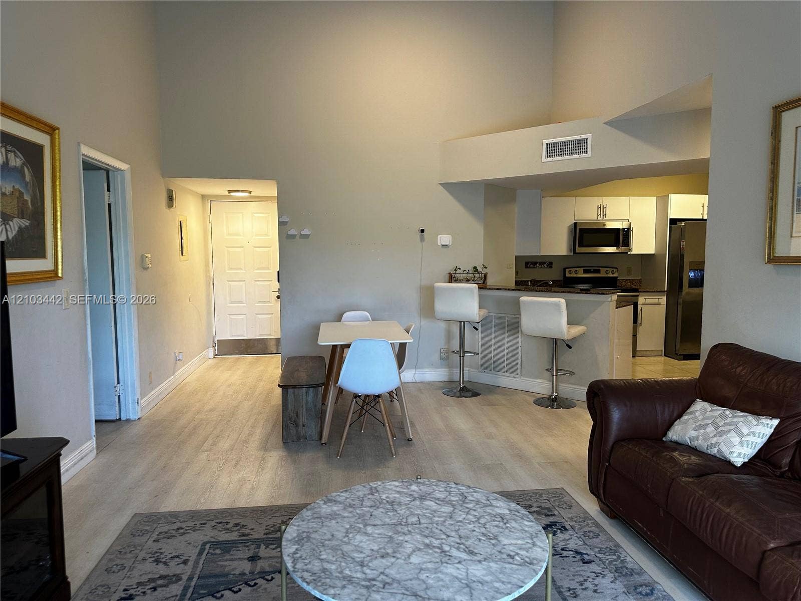 8721 Wiles Road, #303, Coral Springs, FL 33067 High ceilings, wood-finish flooring, and kitchen breakfast bar with overhead lighting