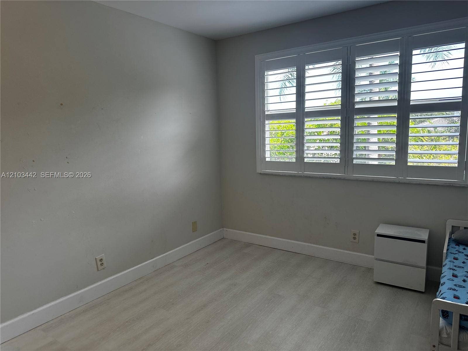 8721 Wiles Road, #303, Coral Springs, FL 33067 Interior room featuring neutral wall paint, wood-finish flooring, and window shutters