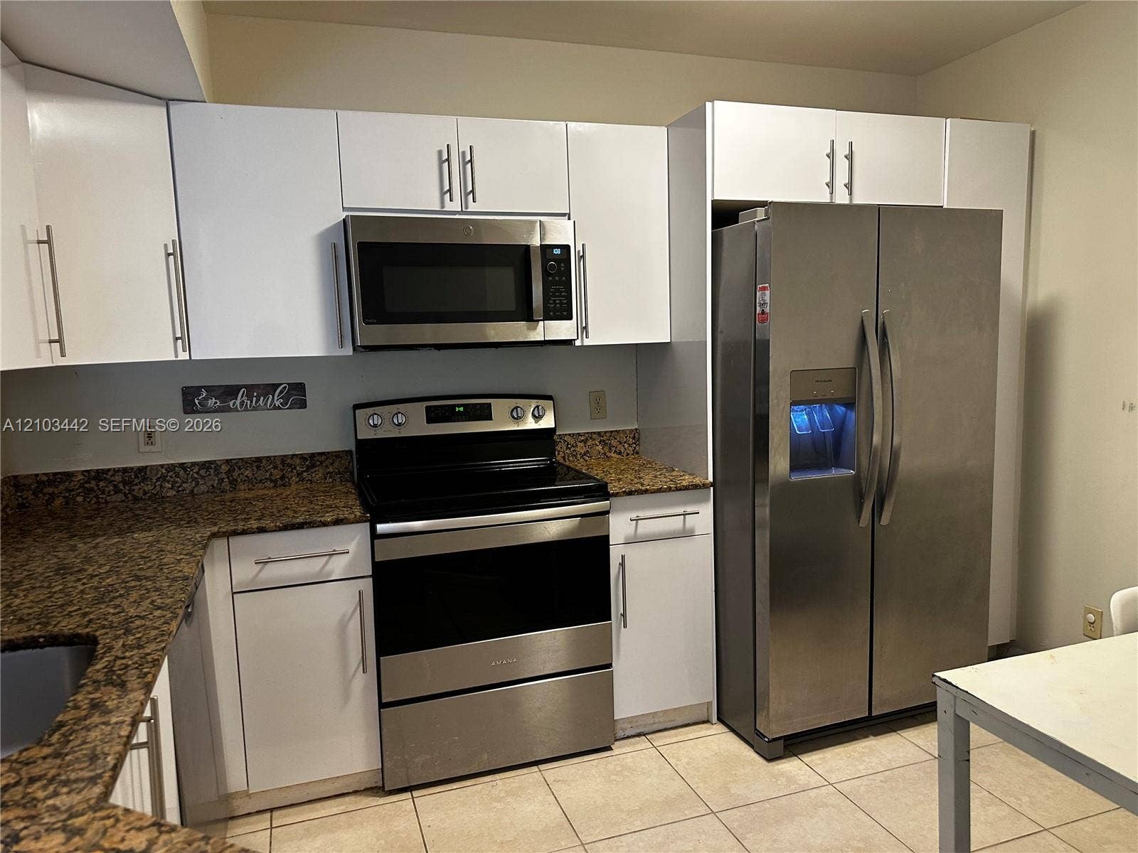 8721 Wiles Road, #303, Coral Springs, FL 33067 Kitchen featuring white flat-panel cabinetry, stone countertops, and stainless steel appliances including a side-by-side refrigerator, over-the-range microwave, and electric range