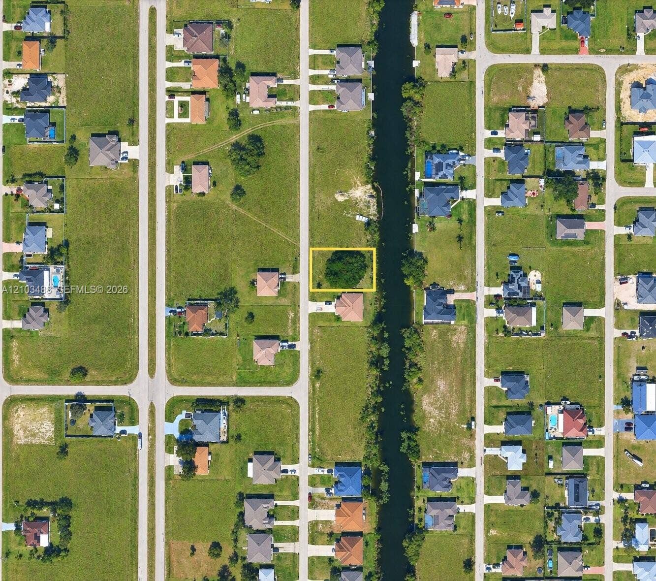 Vacant residential lot featuring direct canal access, established tree canopy, and road frontage