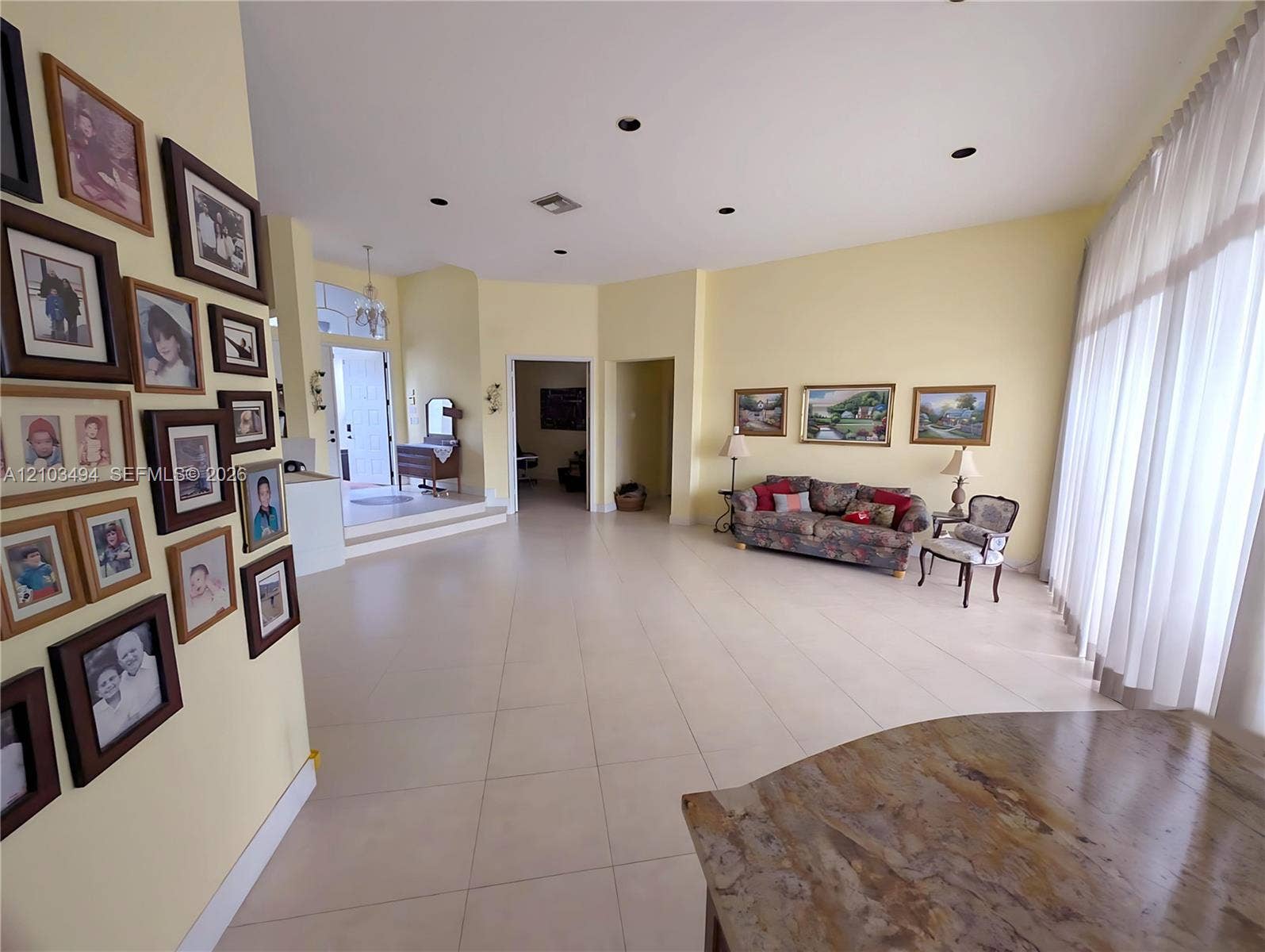 Open-concept room featuring large-format tile flooring, recessed lighting, and expansive floor-to-ceiling windows