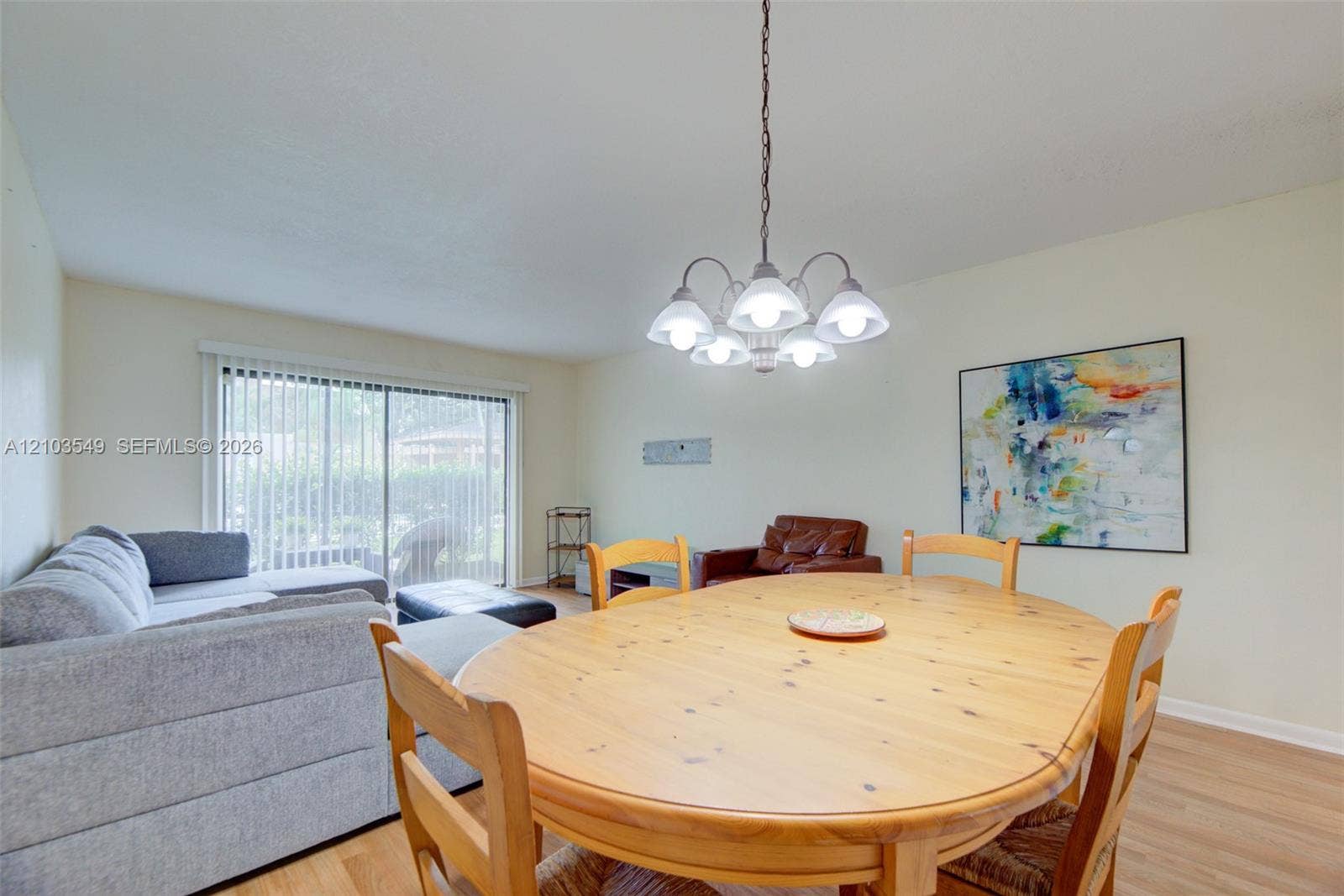8901 N New River Canal Road, #4W, Plantation, Plantation, FL 33324 Open-concept room featuring light-toned wood-finish flooring, a multi-arm chandelier with frosted glass shades, and sliding glass doors