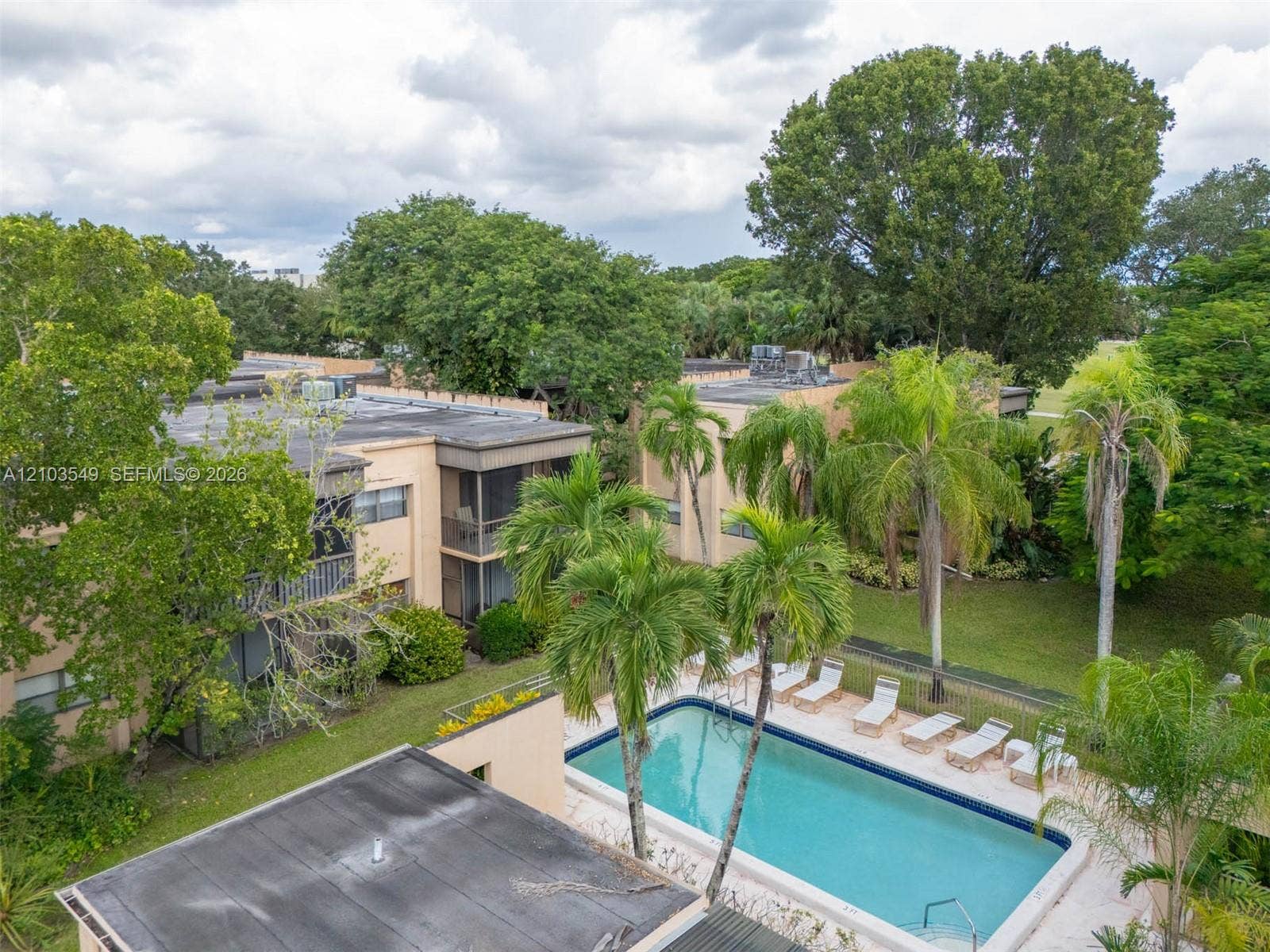 8901 N New River Canal Road, #4W, Plantation, Plantation, FL 33324 Multi-story residential building with screened lanais and stucco exterior, featuring a swimming pool, concrete pool deck, and mature palms