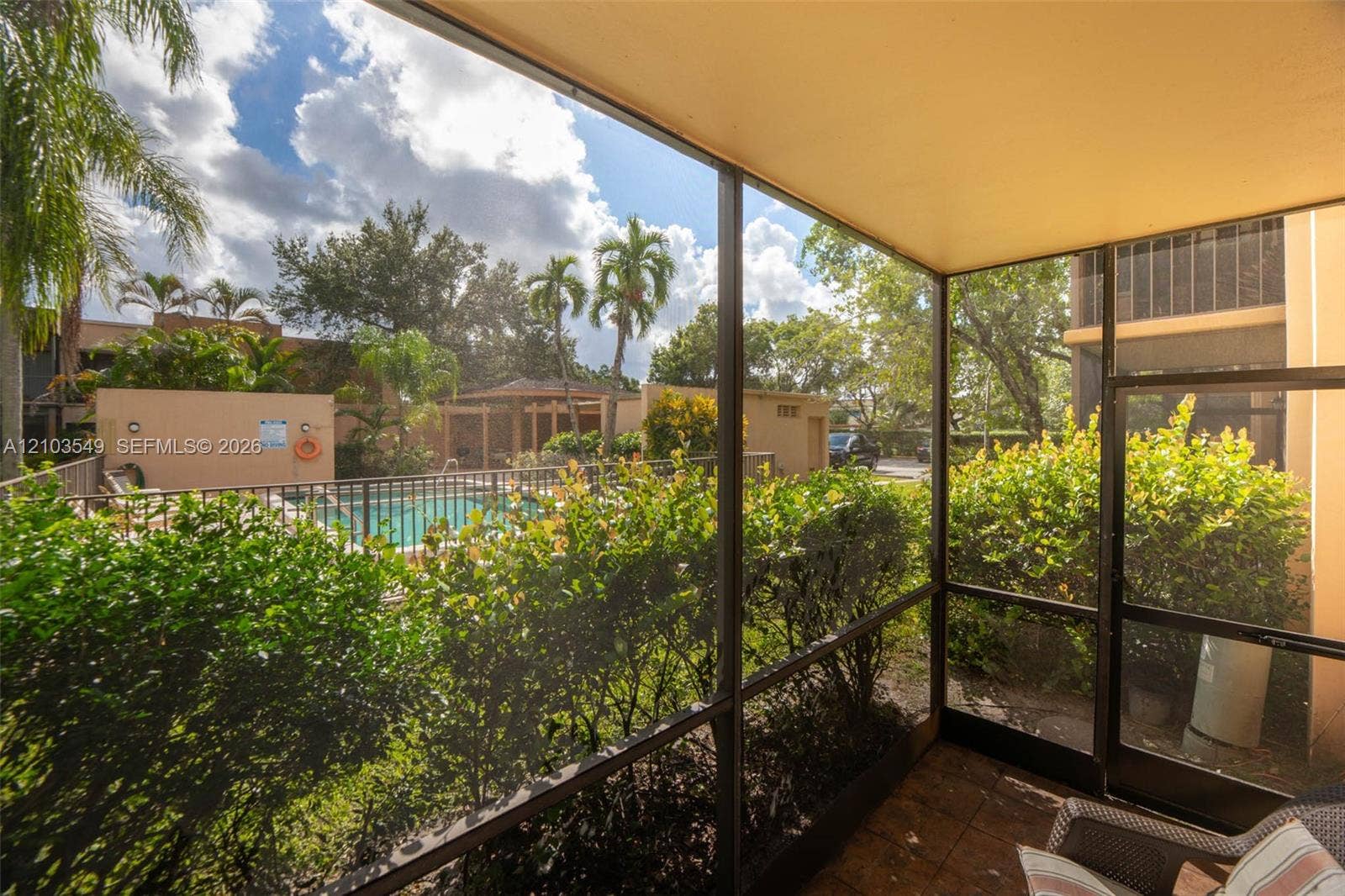8901 N New River Canal Road, #4W, Plantation, Plantation, FL 33324 Screened-in patio featuring tile flooring, metal frame enclosure, and exterior access to a swimming pool and landscaped grounds