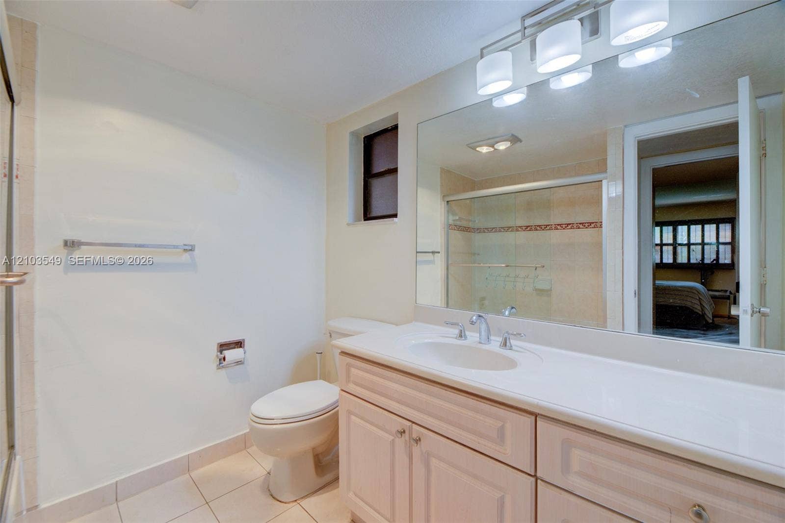 8901 N New River Canal Road, #4W, Plantation, Plantation, FL 33324 Bathroom featuring a vanity with integrated sink and countertop, full-width wall mirror, four-light vanity fixture, and a glass-enclosed shower