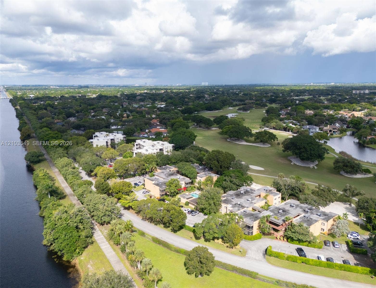 8901 N New River Canal Road, #4W, Plantation, Plantation, FL 33324 Aerial perspective of residential buildings situated along a waterway, featuring a community swimming pool, paved parking areas, and mature landscaping