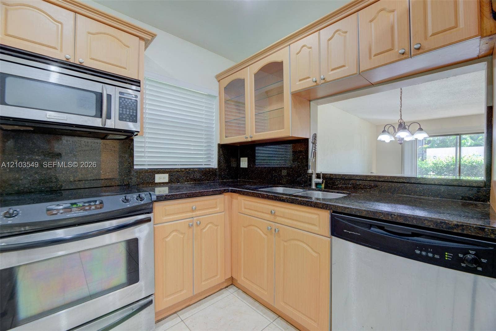 8901 N New River Canal Road, #4W, Plantation, Plantation, FL 33324 Kitchen featuring light-finish cabinetry with glass-front uppers, dark stone-surround countertops, a stainless steel over-the-range microwave, stainless steel range, and a pass-through window