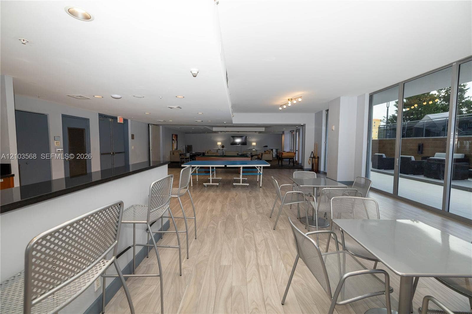 7901 Hispanola Avenue, #801, North Bay Village, FL 33141 Open-concept common area featuring wood-finish flooring, a built-in refreshment bar with a stone countertop, recessed lighting, and expansive floor-to-ceiling glass sliding doors