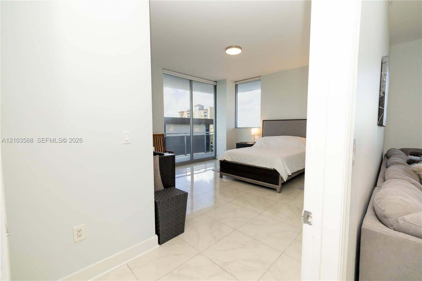 7901 Hispanola Avenue, #801, North Bay Village, FL 33141 Polished stone-finish tile flooring, floor-to-ceiling glass sliding door, balcony access, and large-format windows with integrated roller shades