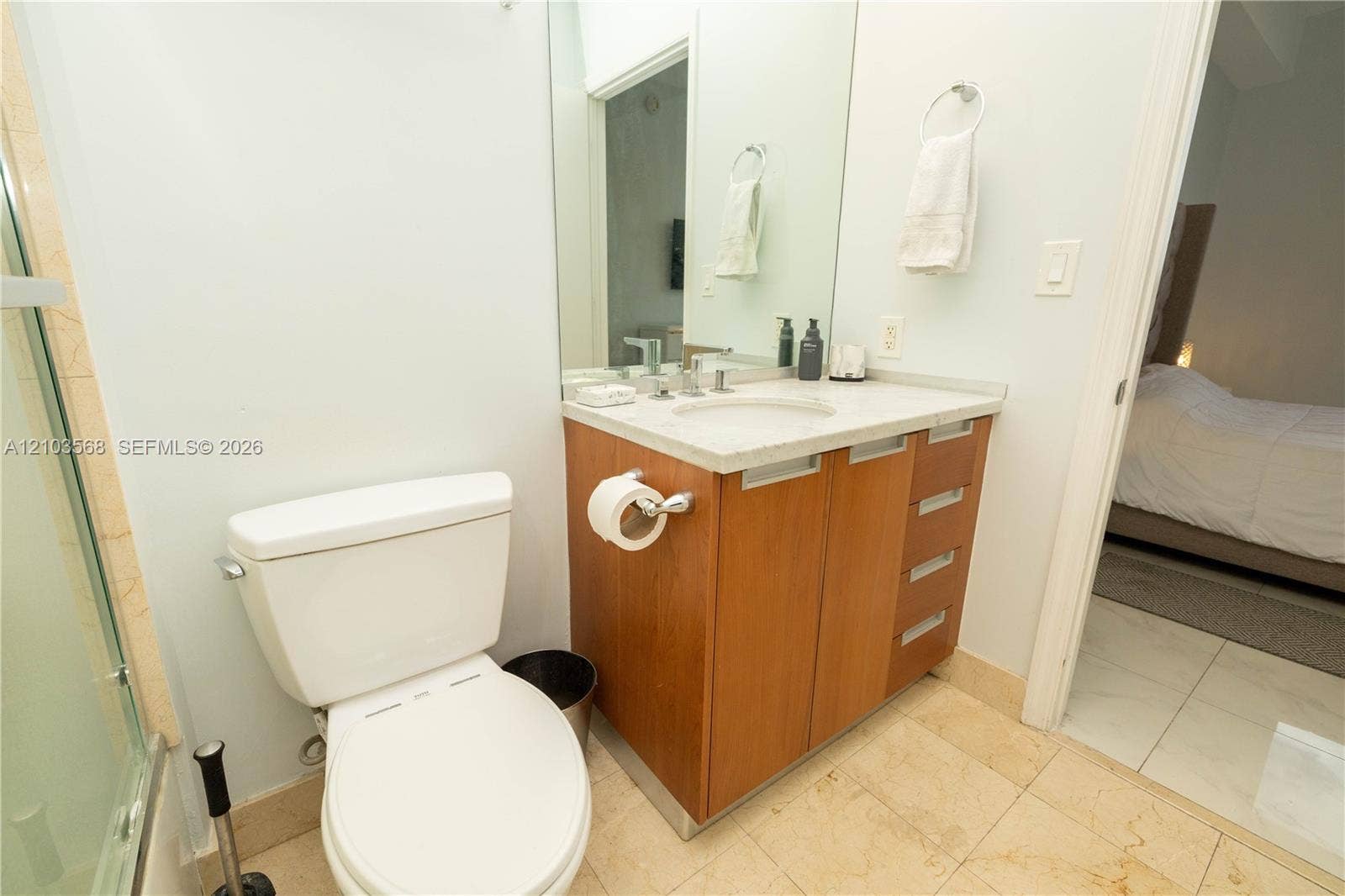 7901 Hispanola Avenue, #801, North Bay Village, FL 33141 Wood-finish vanity with a stone countertop, integrated sink, large wall-mounted mirror, and tile flooring