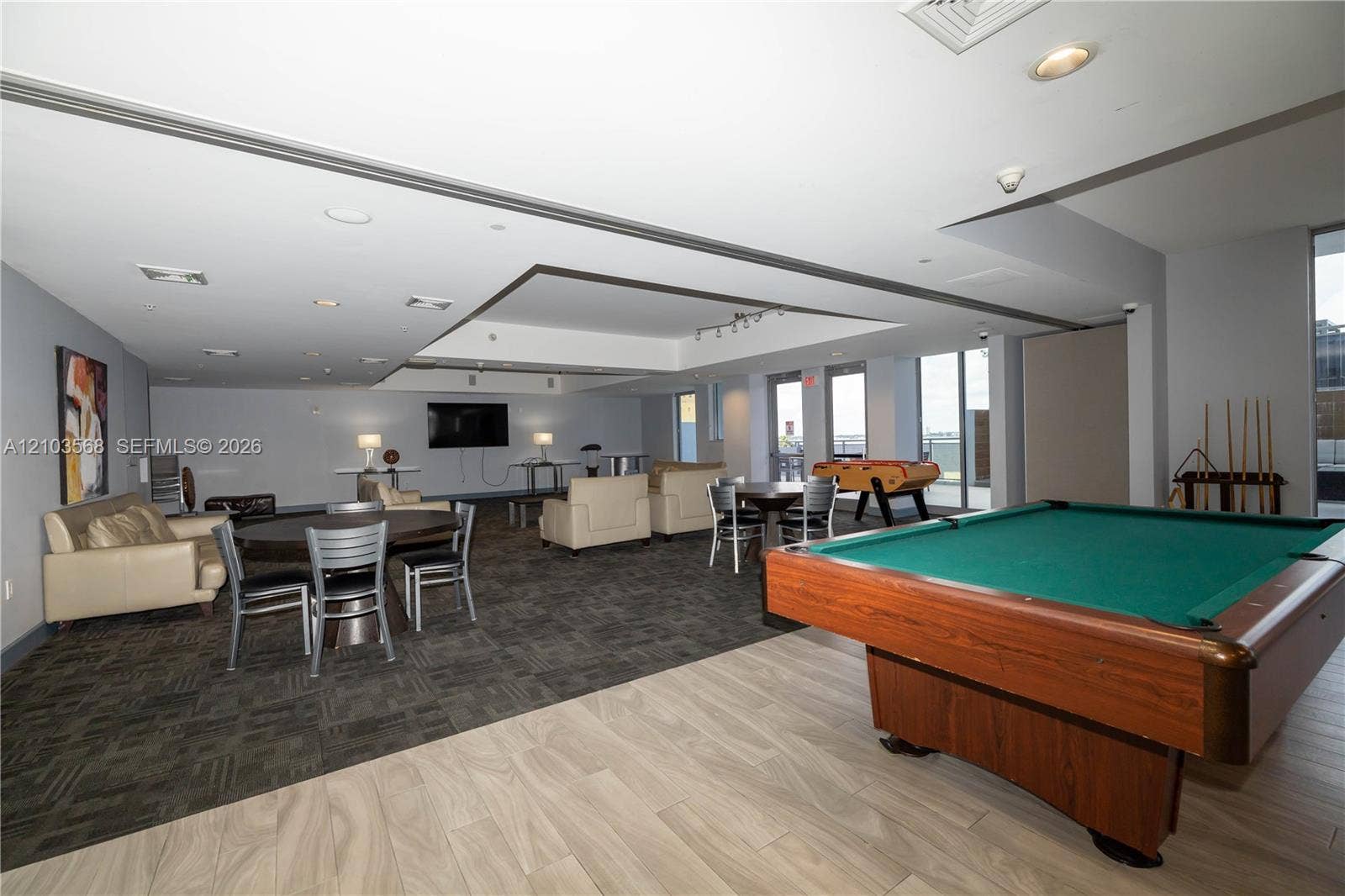 7901 Hispanola Avenue, #801, North Bay Village, FL 33141 Expansive multi-use area featuring recessed ceiling details, wood-finish flooring, patterned carpeting, and floor-to-ceiling glass panel doors