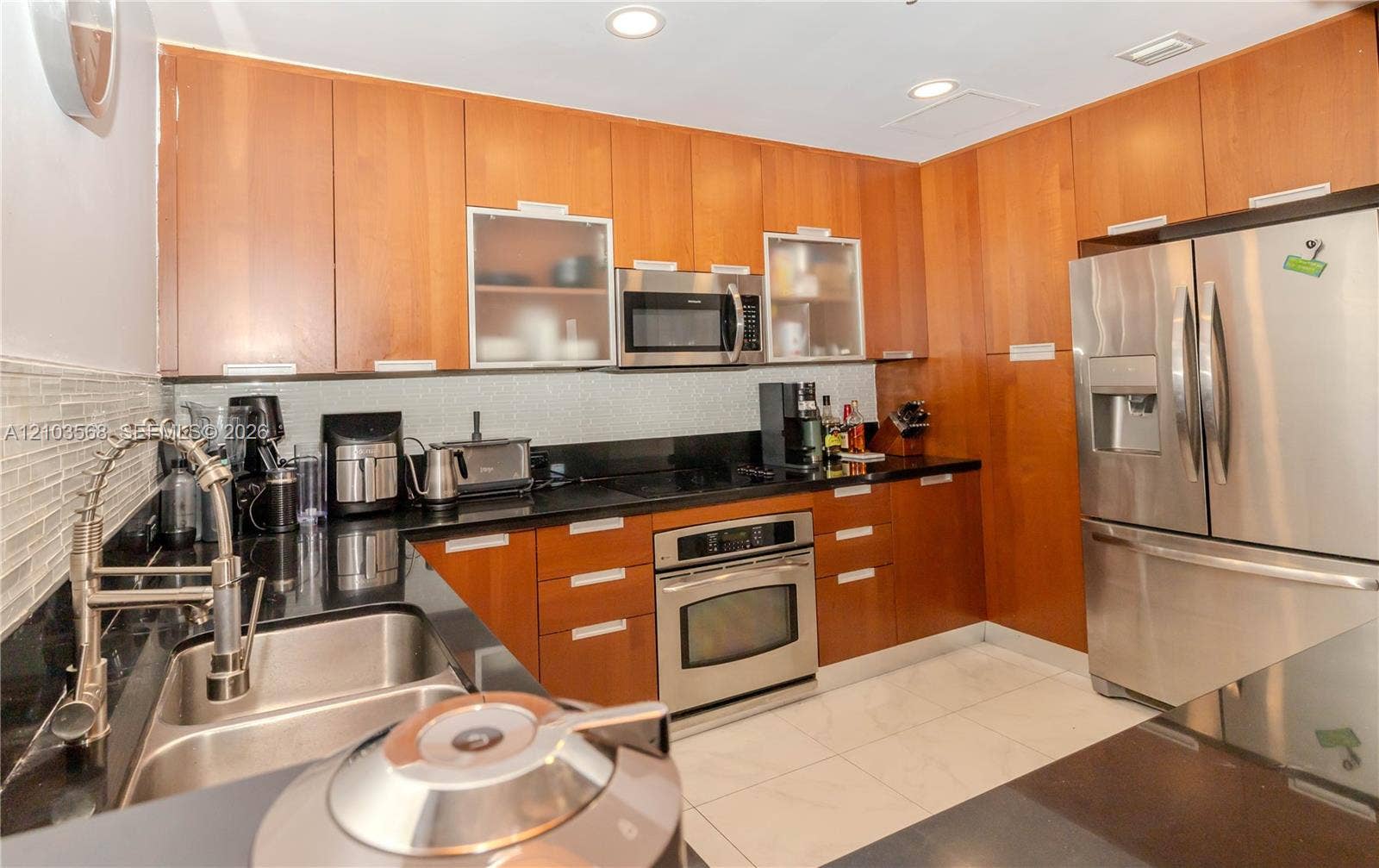 7901 Hispanola Avenue, #801, North Bay Village, FL 33141 Kitchen featuring full-height wood cabinetry, dark stone countertops, stainless steel appliances, a mosaic tile backsplash, and recessed lighting