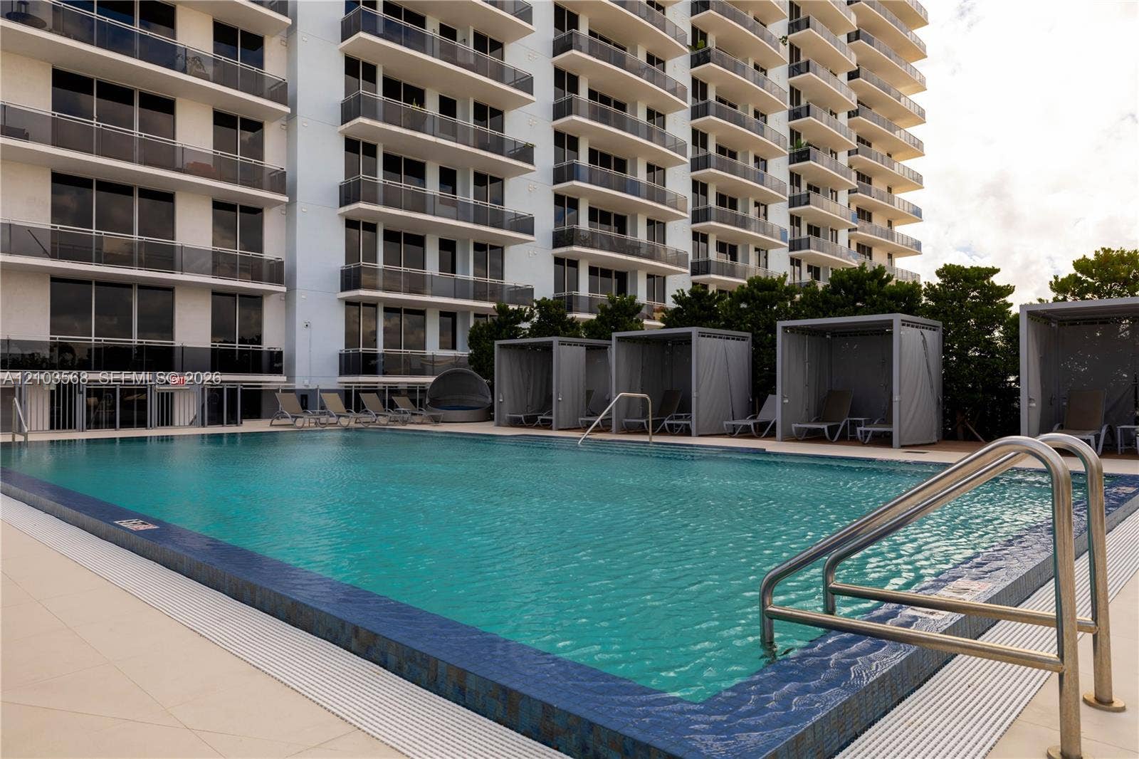 7901 Hispanola Avenue, #801, North Bay Village, FL 33141 Swimming pool featuring tiled coping, metal handrails, and a surrounding paved deck