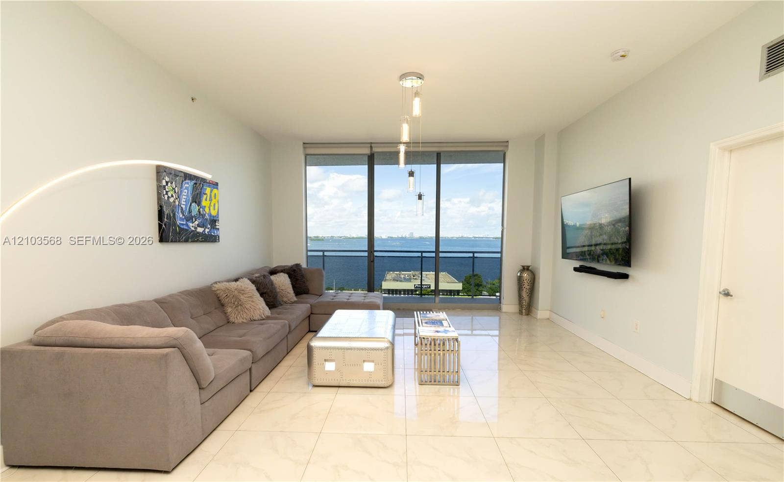 7901 Hispanola Avenue, #801, North Bay Village, FL 33141 Living area featuring large-format tile flooring, floor-to-ceiling glass windows, a private balcony, and pendant lighting