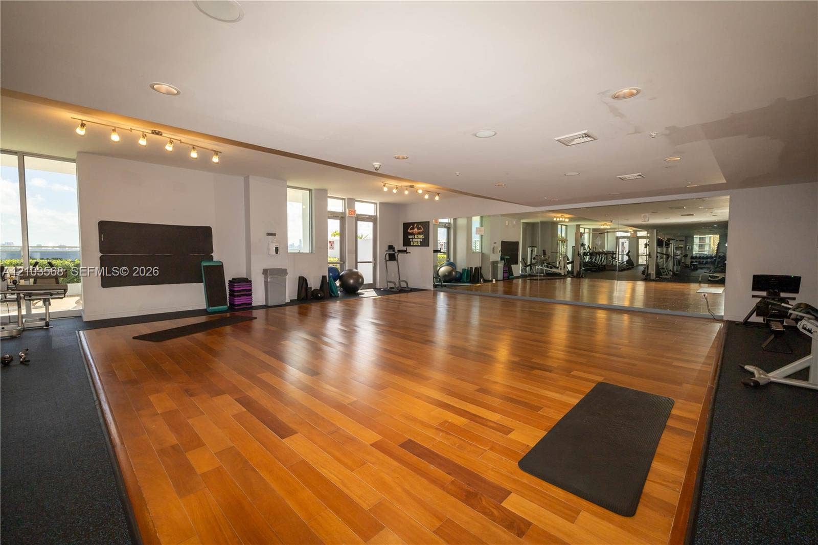 7901 Hispanola Avenue, #801, North Bay Village, FL 33141 Fitness center featuring wood-finish flooring, full-length wall mirrors, recessed lighting, track lighting, and floor-to-ceiling glass doors