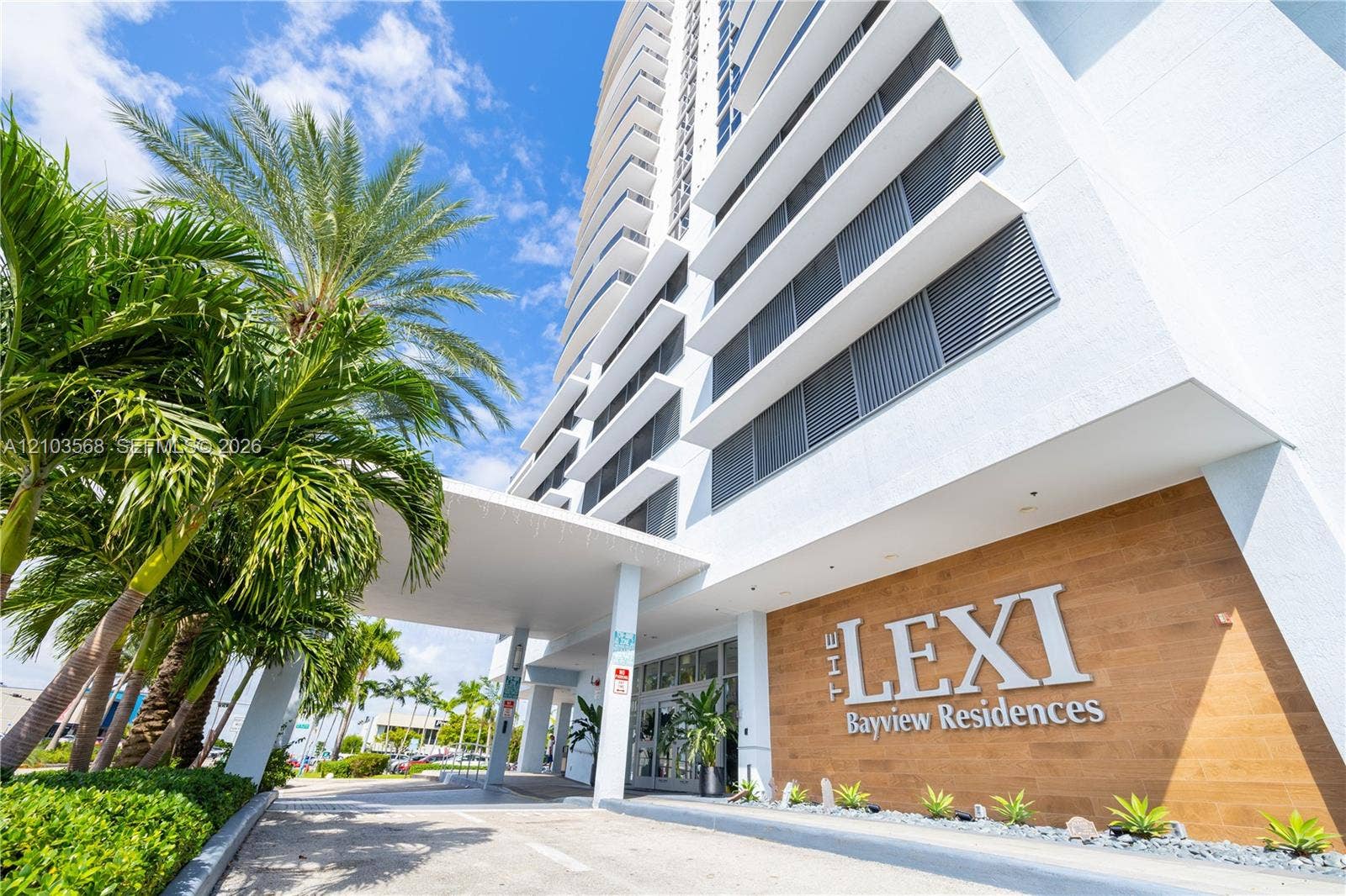 7901 Hispanola Avenue, #801, North Bay Village, FL 33141 High-rise exterior featuring a covered porte-cochre, wood-finish wall cladding, private balconies with horizontal railings, and integrated structural pillars