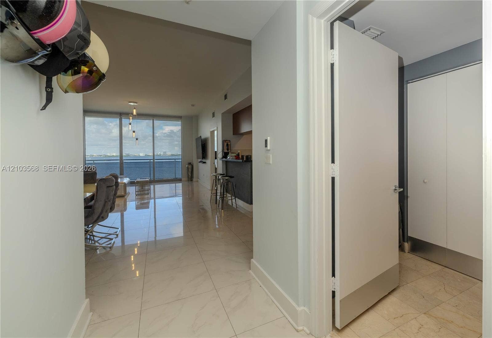 7901 Hispanola Avenue, #801, North Bay Village, FL 33141 Interior entryway featuring large-format light-toned tile flooring, floor-to-ceiling windows, and built-in closet storage with white flat-panel doors