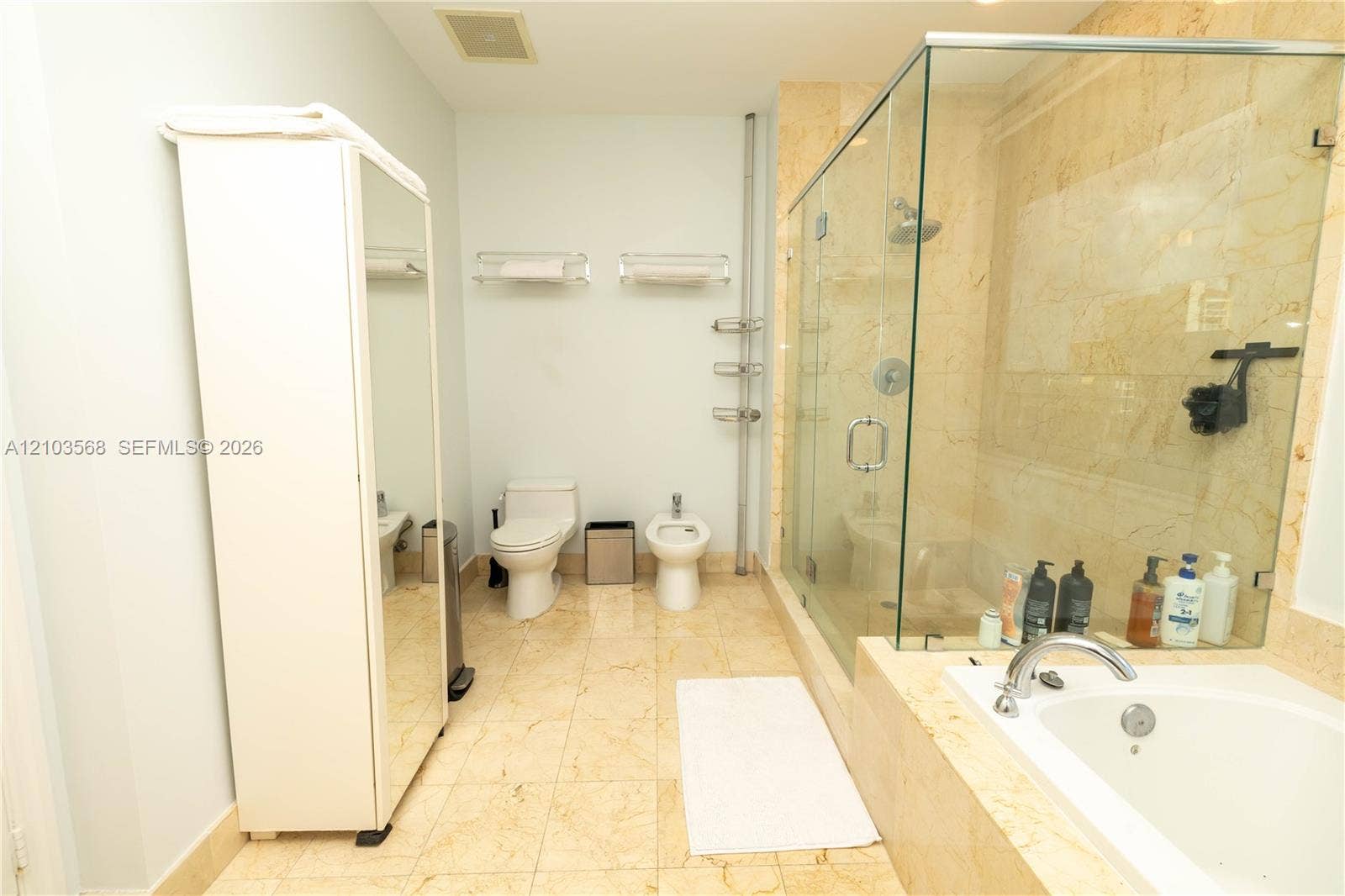 7901 Hispanola Avenue, #801, North Bay Village, FL 33141 Bathroom featuring a stone-tile floor, a glass-enclosed shower with stone-tile surround, and a drop-in soaking tub