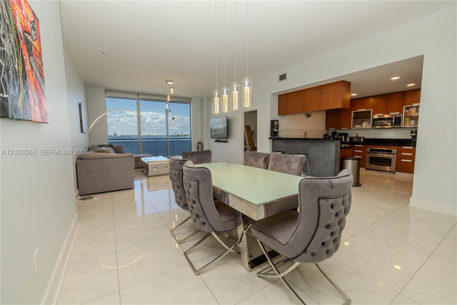 7901 Hispanola Avenue, #801, North Bay Village, FL 33141 Open-concept floor plan featuring large-format polished tile flooring, floor-to-ceiling windows, built-in kitchen cabinetry with integrated stainless steel appliances, and a tiered granite-top breakfast bar