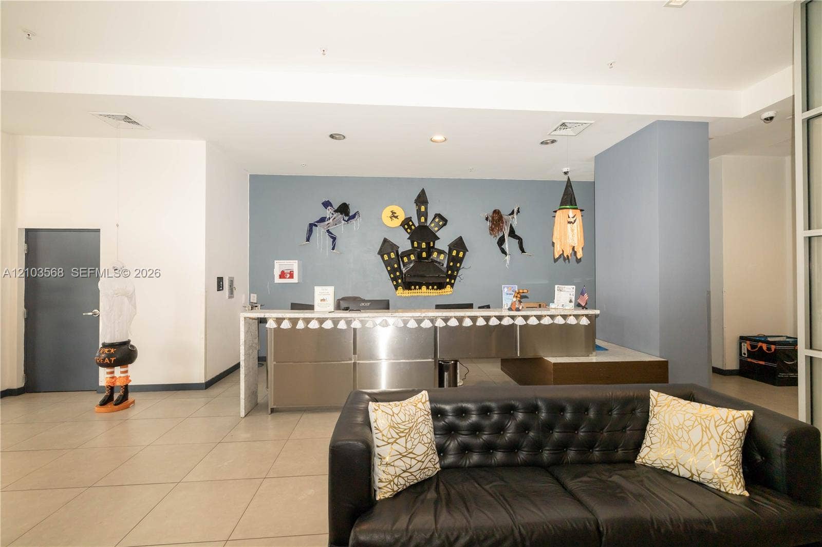 7901 Hispanola Avenue, #801, North Bay Village, FL 33141 Reception area featuring high ceilings, neutral tile flooring, recessed lighting, and a built-in stainless steel desk with a stone-finish countertop