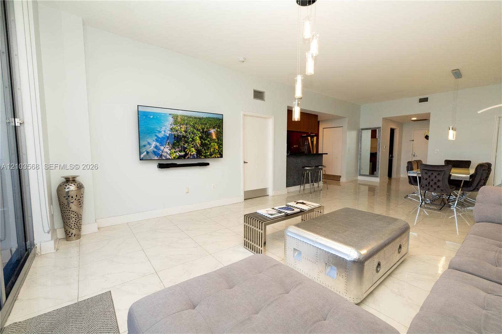 7901 Hispanola Avenue, #801, North Bay Village, FL 33141 Open-concept living space featuring large-format tile flooring, multi-pendant overhead lighting, and a kitchen area with a built-in counter