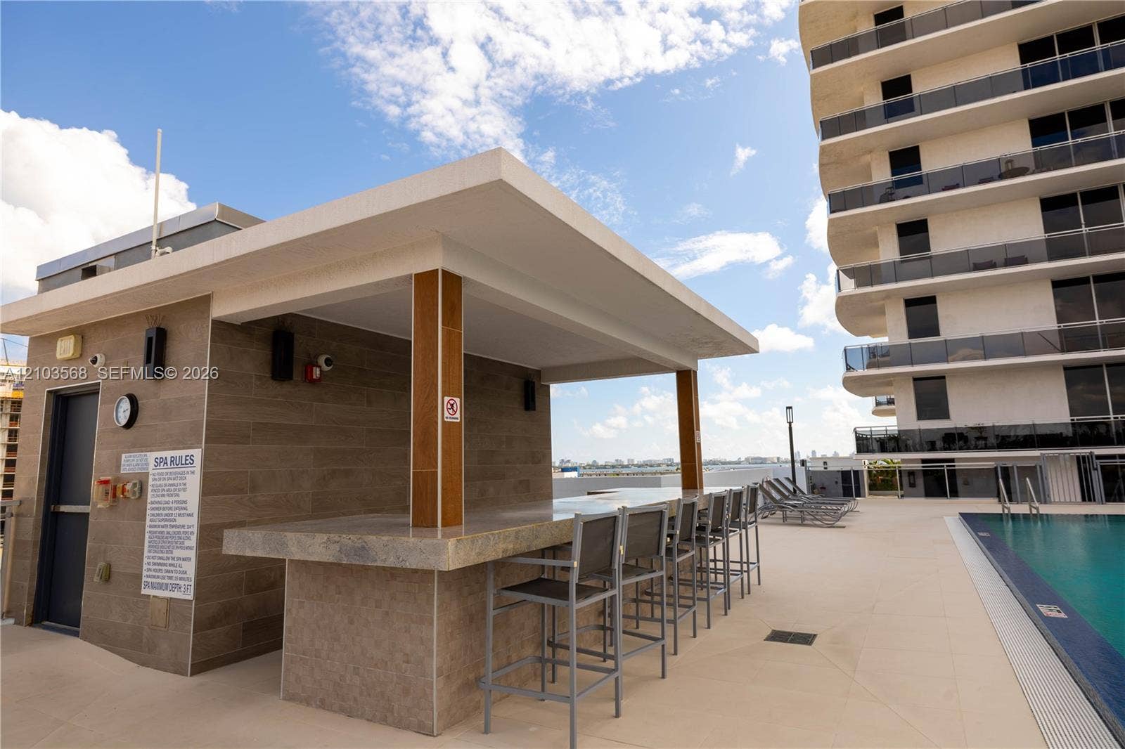 7901 Hispanola Avenue, #801, North Bay Village, FL 33141 Covered outdoor bar featuring tile-clad cabinetry, a stone-finish countertop, and integrated lighting